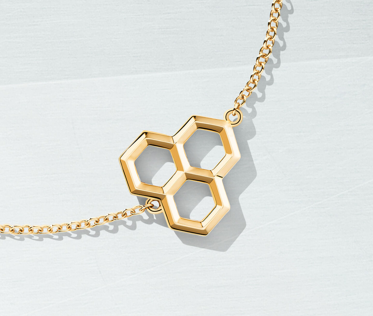 Birks Bee Chic yellow gold bracelet on a light blue background.